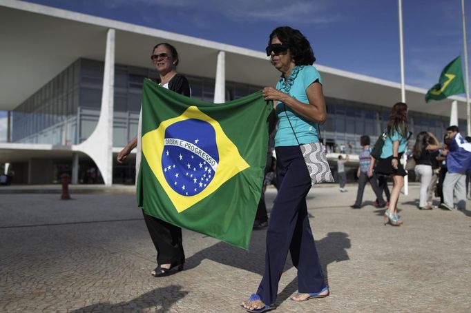 People walk with the Brazilian national flag as they visit the wake of architect Oscar Niemeyer at the Planalto Palace December 6, 2012. Niemeyer, a towering patriarch of modern architecture who shaped the look of modern Brazil and whose inventive, curved designs left their mark on cities worldwide, died late on Wednesday. He was 104. Niemeyer had been battling kidney and stomach ailments in a Rio de Janeiro hospital since early November. His death was the result of a lung infection developed this week, the hospital said, little more than a week before he would have turned 105. REUTERS/Ueslei Marcelino (BRAZIL - Tags: OBITUARY SOCIETY) Published: Pro. 6, 2012, 8:22 odp.