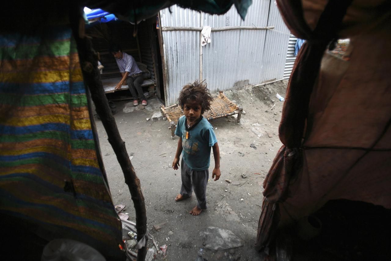 Shivani Choudhary, 7, a street performer, stands in front of her hut in a slum on the bank of Manahara River before leaving to perform on the streets of Kathmandu August 15, 2012. Shivani and her brothers Drumpal and Gchan, who came to Kathmandu from India 5 years ago, earn their living by performing tricks on the streets of Kathmandu. According to Drumpal, Shivani's older brother, they earn around $10 a day by performing tricks, which is not enough to feed their 10-member family living together in a small hut without a proper toilet or any basic needs. REUTERS/Navesh Chitrakar (NEPAL - Tags: SOCIETY IMMIGRATION POVERTY) Published: Srp. 15, 2012, 3:59 odp.