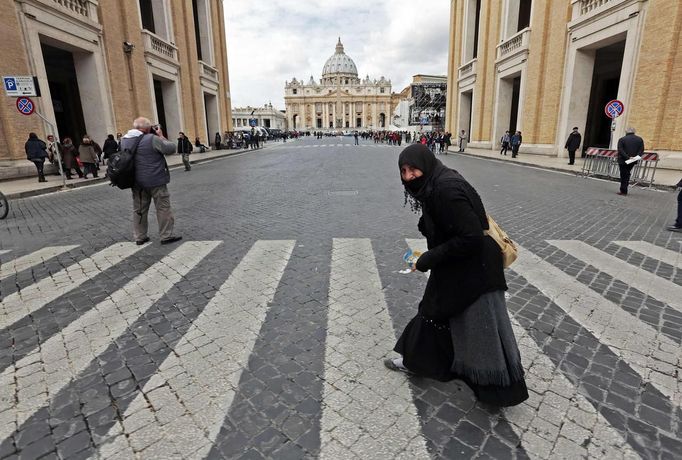 A woman crosses the street in front of Saint Peter's Square at the Vatican March 10, 2013. Roman Catholic cardinals will enter a conclave to elect a successor to Pope Benedict on March 12, the Vatican said on Friday, with no clear favorite emerging so far to take charge of the troubled Church. REUTERS/Eric Gaillard (VATICAN - Tags: RELIGION SOCIETY POVERTY) Published: Bře. 10, 2013, 2:09 odp.