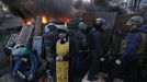 Anti-government protesters and a priest look out from a barricade in Kiev February 21, 2014.