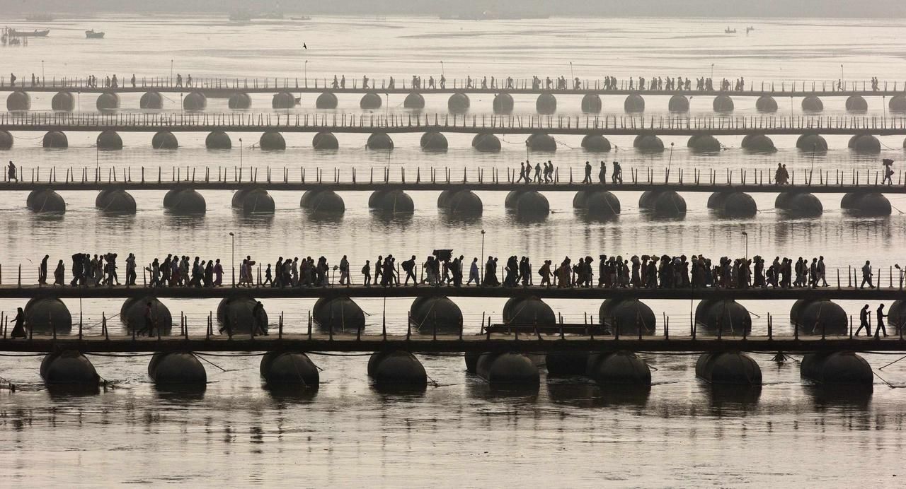 Hindu devotees cross pontoon bridges spanning the river Ganges during the first "Shahi Snan" (grand bath) at the ongoing "Kumbh Mela", or Pitcher Festival, in the northern Indian city of Allahabad January 14, 2013. Upwards of a million elated Hindu holy men and pilgrims took a bracing plunge in India's sacred Ganges river to wash away lifetimes of sins on Monday, in a raucous start to an ever-growing religious gathering that is already the world's largest. REUTERS/Ahmad Masood (INDIA - Tags: RELIGION SOCIETY) Published: Led. 14, 2013, 2:02 odp.