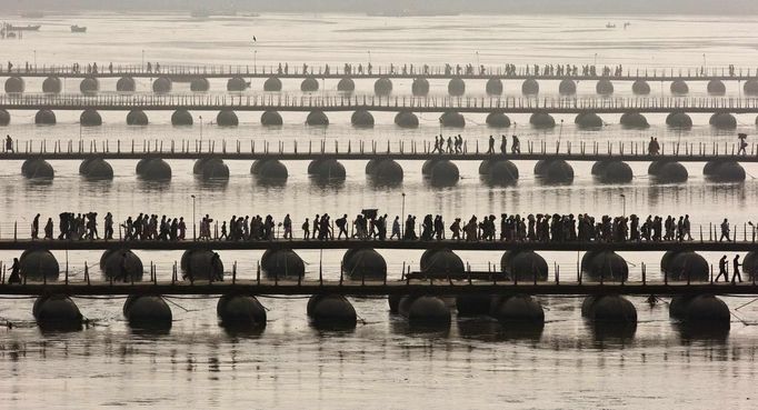 Hindu devotees cross pontoon bridges spanning the river Ganges during the first "Shahi Snan" (grand bath) at the ongoing "Kumbh Mela", or Pitcher Festival, in the northern Indian city of Allahabad January 14, 2013. Upwards of a million elated Hindu holy men and pilgrims took a bracing plunge in India's sacred Ganges river to wash away lifetimes of sins on Monday, in a raucous start to an ever-growing religious gathering that is already the world's largest. REUTERS/Ahmad Masood (INDIA - Tags: RELIGION SOCIETY) Published: Led. 14, 2013, 2:02 odp.