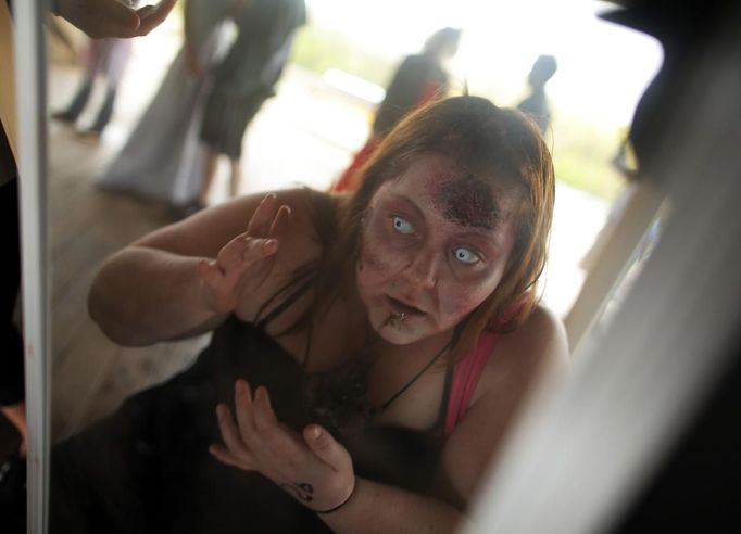 A zombie checks her make-up in a mirror before chasing runners on the "Run for Your Lives" 5K obstacle course race in Amesbury, Massachusetts May 5, 2012. Runners face man-made and natural obstacles on the course, while being chased by zombies, who try to take "health" flags off the runners belts. REUTERS/Brian Snyder (UNITED STATES) Published: Kvě. 5, 2012, 11:20 odp.