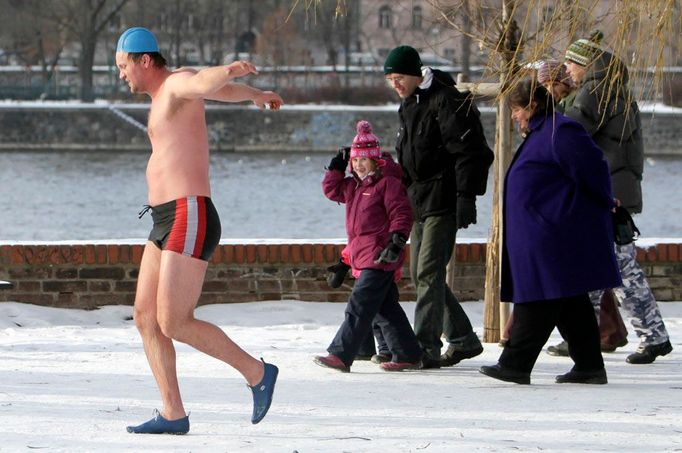 Odvaha, nad kterou zůstává rozum stát. Lidé v Praze přihlížejí, jak se otužilec chystá na Štěpána ponořit do chladných vod Vltavy.