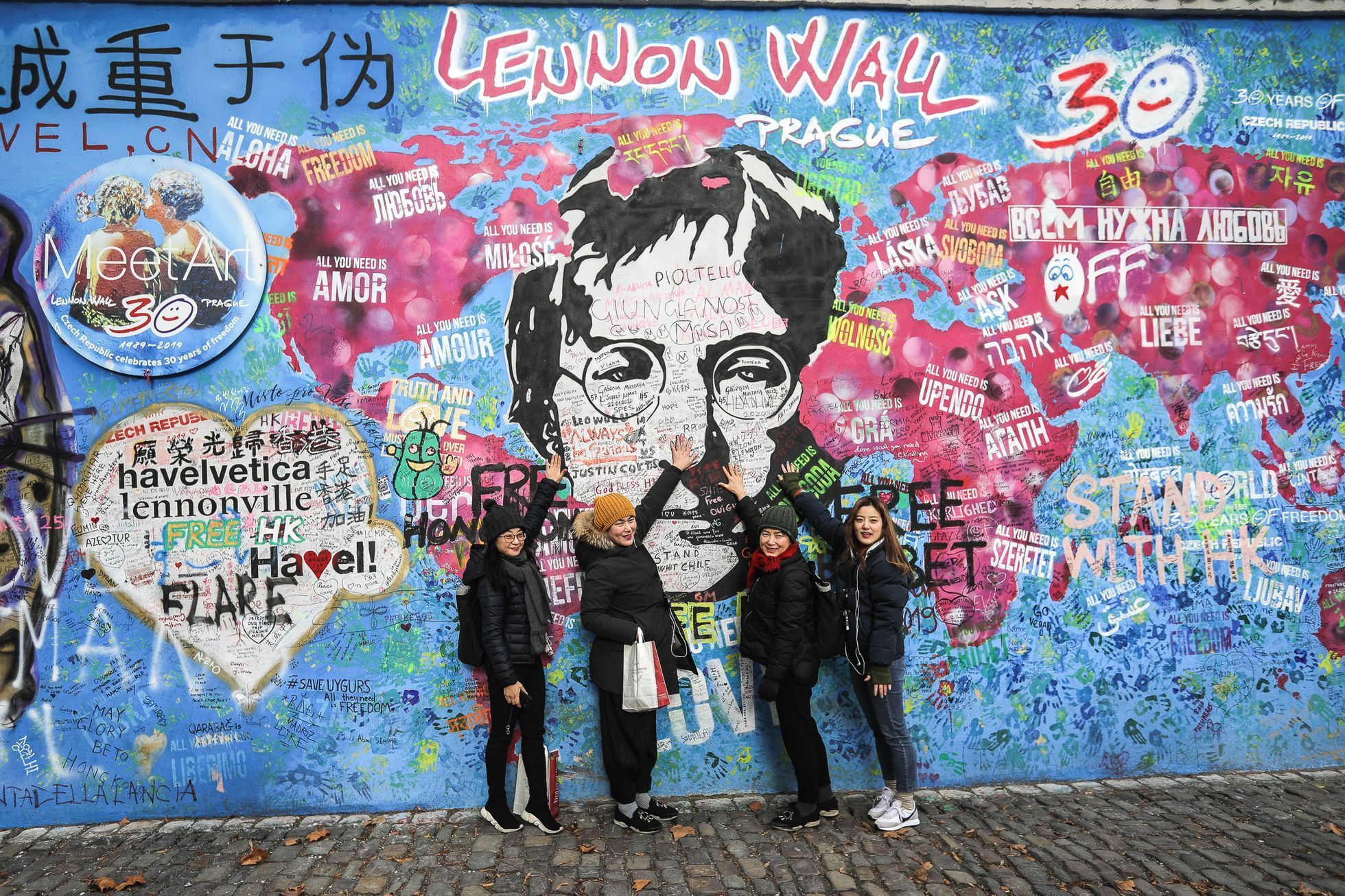 Lennonova zeď po třech měsících od malování - turisté, graffiti