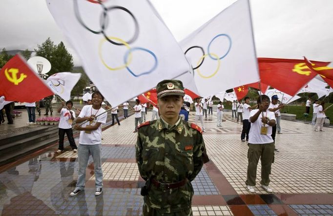 A People's Liberation Army (PLA) soldier stand guards as organized participants wave flags during the opening ceremony of the Olympic torch relay in Lhasa, Tibet June 21, 2008. REUTERS/Nir Elias (CHINA) (BEIJING OLYMPICS 2008 PREVIEW)