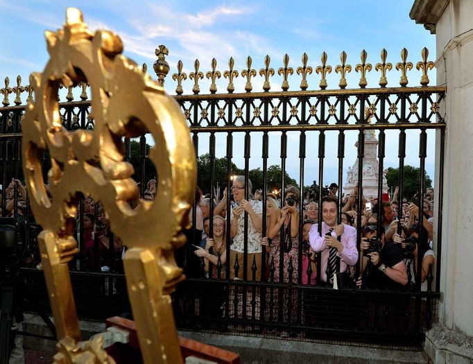 Davy před Buckinghamským palácem v Londýně. Všichni si chtějí přečíst, co je na oficiální vávěsce na stojanu u brány.