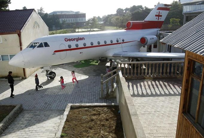 Children walk next to a plane at a kindergarten in the town of Rustavi some 25 km (15 miles) south of Tbilisi, October 31, 2012. The fully functional Soviet-era Yakovlev Yak-40 plane has been installed in the kindergarten courtyard and refurbished as a children's playground. REUTERS/David Mdzinarishvili (GEORGIA - Tags: EDUCATION SOCIETY) Published: Říj. 31, 2012, 11:18 dop.