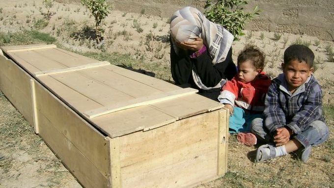 Žena s dětmi oplakává svého muže, který byl zabit v Bagdádu 22. listopadu.