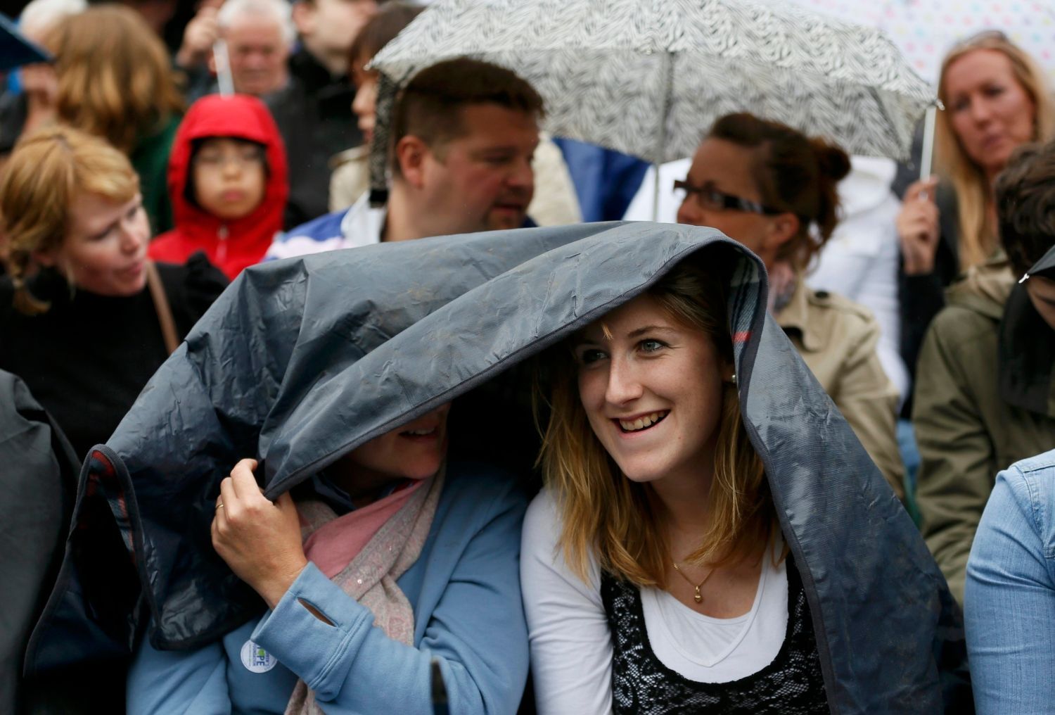 Fanynky se skrývají před deštěm během utkání mezi Andym Murraym a Marinem Čiličem v osmifinále Wimbledonu 2012.
