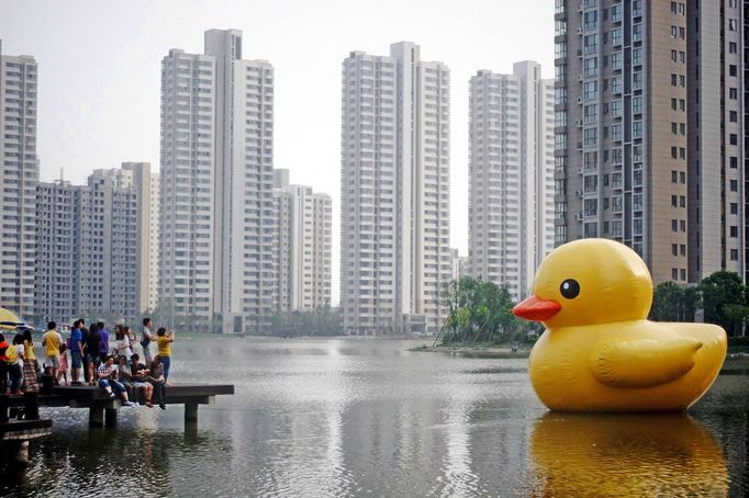 People look at a six-meter-tall aired Rubber Duck, funded by the local community, floating in a lake of a residential block in north China's Tianjin Municipality Saturday June 1, 2013.