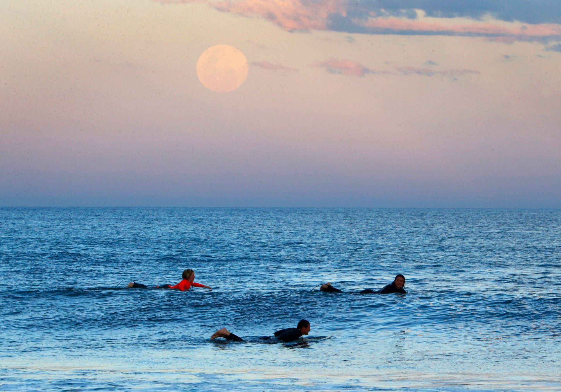 Surfers wait for waves as supermoon rises off Sydney beachside suburb of Wanda