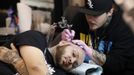 A tattoo artist works on the head of a client during the second annual Hampton Roads Tattoo Festival in Virginia March 2, 2012. The hobby of collecting tattoos has exploded into the mainstream of society with tattoo conventions and festivals held year-round across the United States. Picture taken March 2, 2012. REUTERS/Jason Reed (UNITED STATES - Tags: SOCIETY) ATTENTION EDITORS PICTURE 04 OF 31 FOR PACKAGE 'ADDICTED TO THE NEEDLE' TO FIND ALL PICTURES SEARCH 'ADDICTED NEEDLE' Published: Čer. 29, 2012, 12:58 odp.