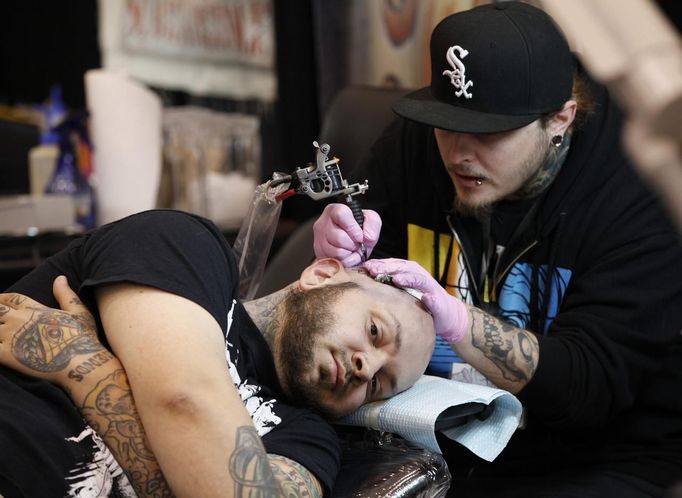 A tattoo artist works on the head of a client during the second annual Hampton Roads Tattoo Festival in Virginia March 2, 2012. The hobby of collecting tattoos has exploded into the mainstream of society with tattoo conventions and festivals held year-round across the United States. Picture taken March 2, 2012. REUTERS/Jason Reed (UNITED STATES - Tags: SOCIETY) ATTENTION EDITORS PICTURE 04 OF 31 FOR PACKAGE 'ADDICTED TO THE NEEDLE' TO FIND ALL PICTURES SEARCH 'ADDICTED NEEDLE' Published: Čer. 29, 2012, 12:58 odp.