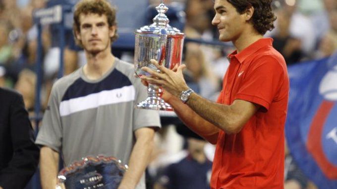 Roger Federer rozdává úsměvy s trofejí pro vítěze US Open, sleduje ho viditelně zklamaný Andy Murray.