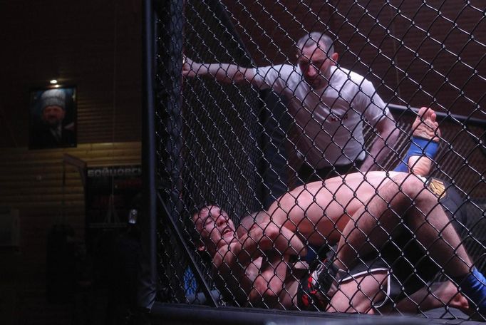 Participants in a local mixfight competition wrestle in the ring, with a portrait of former Chechen leader Akhmad Kadyrov in the background in the village of Goryachevodsk, Russia April 24, 2013. The naming of two Chechens, Dzhokhar and Tamerlan Tsarnaev, as suspects in the Boston Marathon bombings has put Chechnya - the former site of a bloody separatist insurgency - back on the world's front pages. Chechnya appears almost miraculously reborn. The streets have been rebuilt. Walls riddled with bullet holes are long gone. New high rise buildings soar into the sky. Spotless playgrounds are packed with children. A giant marble mosque glimmers in the night. Yet, scratch the surface and the miracle is less impressive than it seems. Behind closed doors, people speak of a warped and oppressive place, run by a Kremlin-imposed leader through fear. Picture taken April 24, 2013. REUTERS/Maxim Shemetov (RUSSIA - Tags: SOCIETY POLITICS SPORT BOXING) ATTENTION EDITORS: PICTURE 25 OF 40 FOR PACKAGE 'INSIDE MODERN CHECHNYA'. SEARCH 'REBUILDING CHECHNYA' FOR ALL IMAGES Published: Kvě. 1, 2013, 8:06 dop.