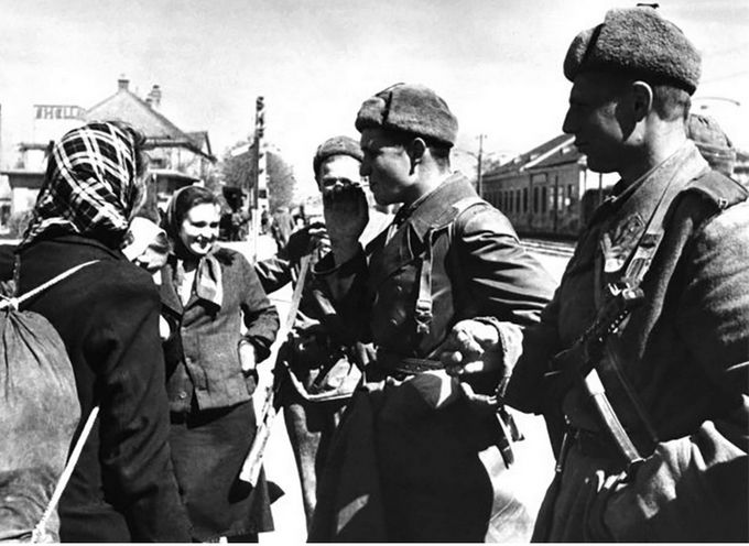 Sovětští vojáci hovoří s osvobozenými nuceně nasazenými pracovníky ze Sovětského svazu ve Vídni, duben 1945, krátce po osvobození města od nacistů.