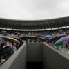 Fanoušci se skrývají před deštěm během utkání mezi Andym Murraym a Marinem Čiličem v osmifinále Wimbledonu 2012.
