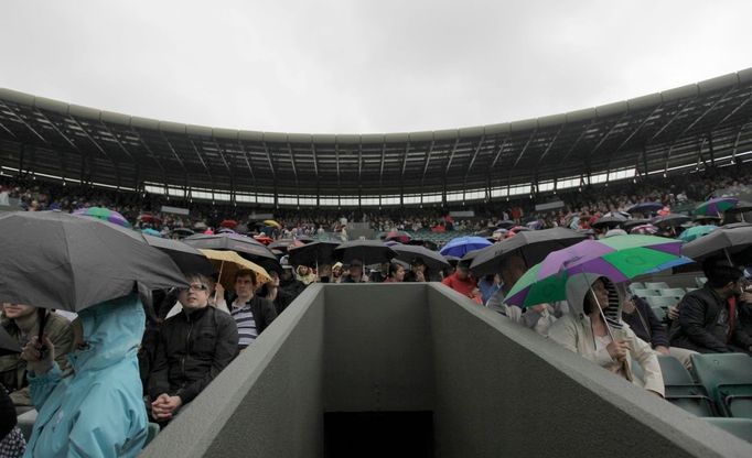 Fanoušci se skrývají před deštěm během utkání mezi Andym Murraym a Marinem Čiličem v osmifinále Wimbledonu 2012.