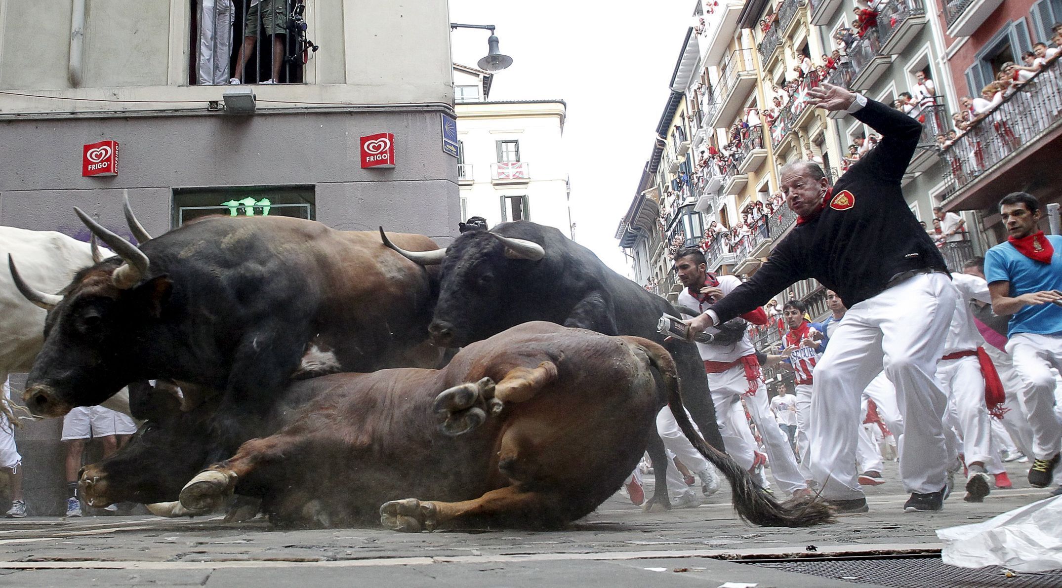 An El Tajo y La Reina ranch fighting bull falls to the ground as it takes the Mercaderes curve during the second running of the bulls of the San Fermin festival in Pamplona