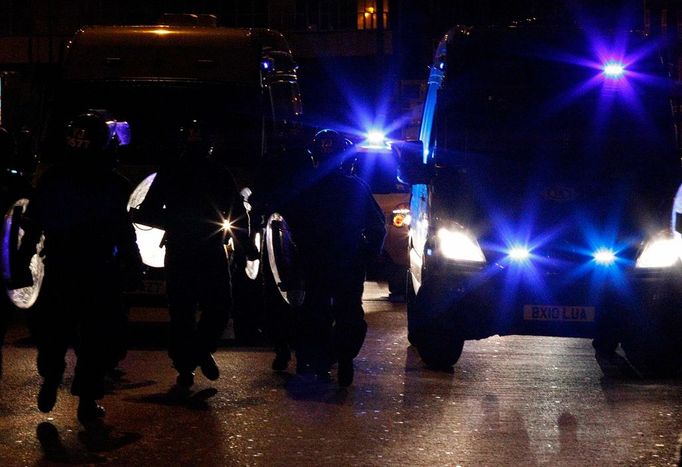 Policisté nasazení proti výtržníkům v Birminghamu se znaveně vrací ke svým vozidlům.