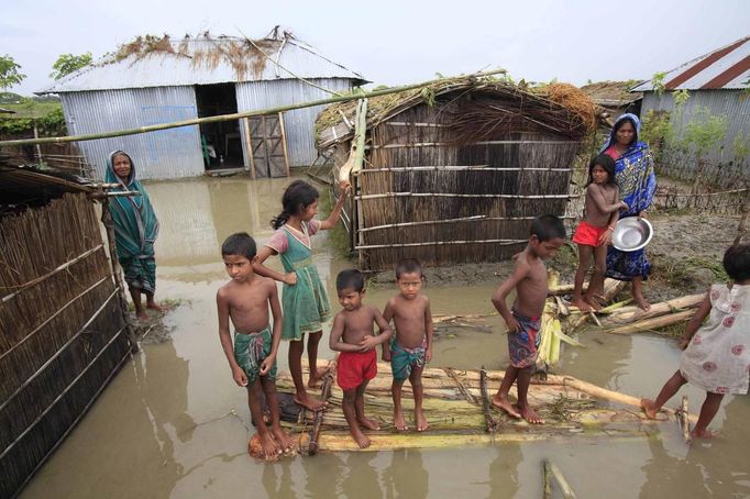 BANGLADESH-FLOODS/ Description: Children stand on a makeshift banana plant raft in front of their house at a flooded village in Kurigram July 3, 2012. At least 100 people have died and hundreds of thousands of people are marooned as floods triggered by heavy rains spread across Bangladesh. REUTERS/Andrew Biraj (BANGLADESH - Tags: DISASTER ENVIRONMENT) Published: Čec. 3, 2012, 10:16 dop.