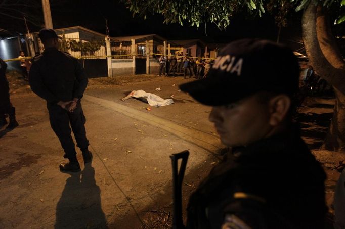 Police officers guard a crime scene near the body of a victim in the city of San Pedro Sula March 22, 2013. Unknown assailants killed three men and one woman on Friday at the crime scene in a working class neighbourhood, local media reported. San Pedro Sula has been labelled the most violent city on the planet, according to a U.N. Development Program report last week. Picture taken March 22, 2013. REUTERS/Jorge Cabrera (HONDURAS - Tags: CIVIL UNREST CRIME LAW) Published: Bře. 23, 2013, 9:08 odp.