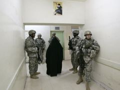 Iráčanka prochází v nemocniční chodbě kolem skupinky amerických vojáků.