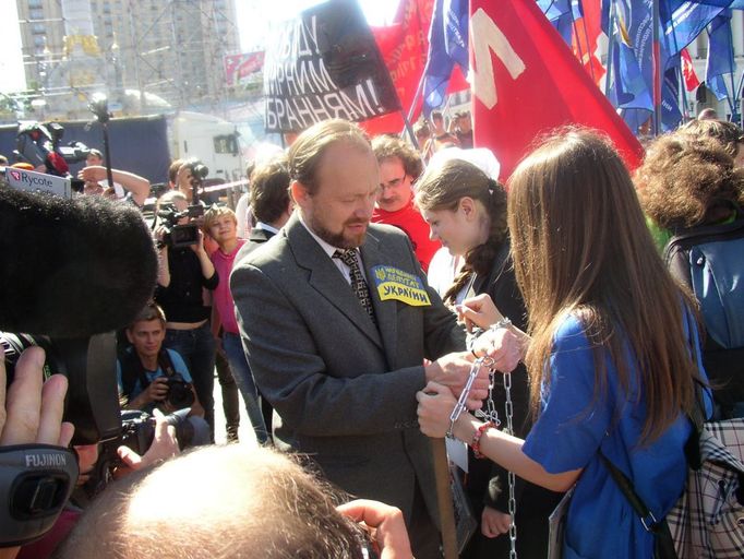 Poslanec ,,spoutává" řetězem protestující.