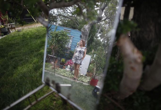 Dora Viesca, 52, poses for a photo outside her trailer in which she has lived for 21 years, in Village Trailer Park in Santa Monica, California, July 13, 2012. Developer Marc Luzzatto wants to relocate residents from the trailer park to make way for nearly 500 residences, office space, stores, cafes and yoga studios, close to where a light rail line is being built to connect downtown Los Angeles to the ocean. Village Trailer Park was built in 1951, and 90 percent of its residents are elderly, disabled or both, according to the Legal Aid Society. Many have lived there for decades in old trailers which they bought. The property is valued at as much as $30 million, according the LA Times. REUTERS/Lucy Nicholson (UNITED STATES - Tags: SOCIETY REAL ESTATE BUSINESS POLITICS) Published: Čec. 14, 2012, 7:41 dop.