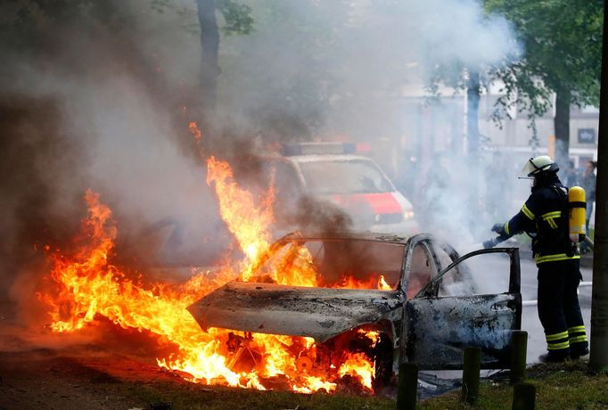 Hasič hasí hořící auto v Hamburku.