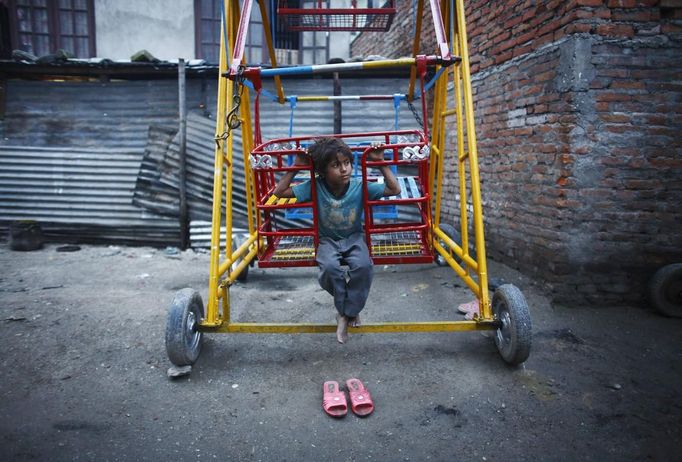 Shivani Choudhary, 7, a street performer rests on a ferris wheel near her hut at the slum on the bank of Manahara River after a whole day of street performance in Kathmandu August 15, 2012. Shivani and her brothers Drumpal and Gchan, who came to Kathmandu from India 5 years ago, earn their living by performing tricks on the streets of Kathmandu. According to Drumpal, Shivani's older brother, they earn around $10 a day by performing tricks, which is not enough to feed their 10-member family living together in a small hut without a proper toilet or any basic needs. REUTERS/Navesh Chitrakar (NEPAL - Tags: SOCIETY POVERTY IMMIGRATION) Published: Srp. 15, 2012, 4:33 odp.