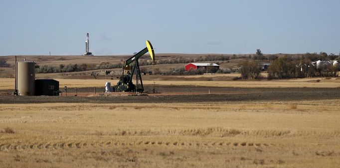 A farm is situated between an oil drilling rig and an oil pump jack outside Watford, North Dakota, October 20, 2012. Thousands of people have flooded into North Dakota to work in state's oil drilling boom. Picture taken October 20, 2012. REUTERS/Jim Urquhart (UNITED STATES - Tags: ENERGY ENVIRONMENT BUSINESS EMPLOYMENT) Published: Říj. 22, 2012, 1:40 odp.