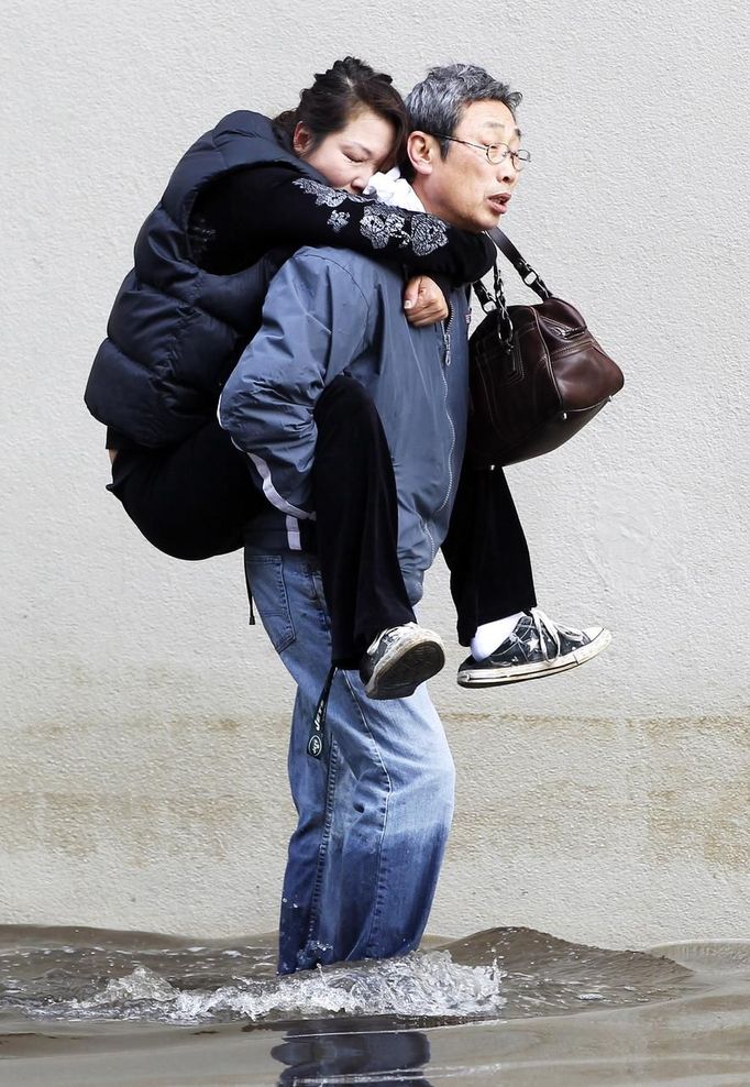 A man carries his wife through the floodwaters in Hoboken, New Jersey, October 31, 2012. The U.S. Northeast began crawling back to normal on Wednesday after monster storm Sandy crippled transportation, knocked out power for millions and killed at least 45 people in nine states with a massive storm surge and rain that caused epic flooding. REUTERS/Gary Hershorn (UNITED STATES - Tags: ENVIRONMENT DISASTER) Published: Říj. 31, 2012, 8:22 odp.