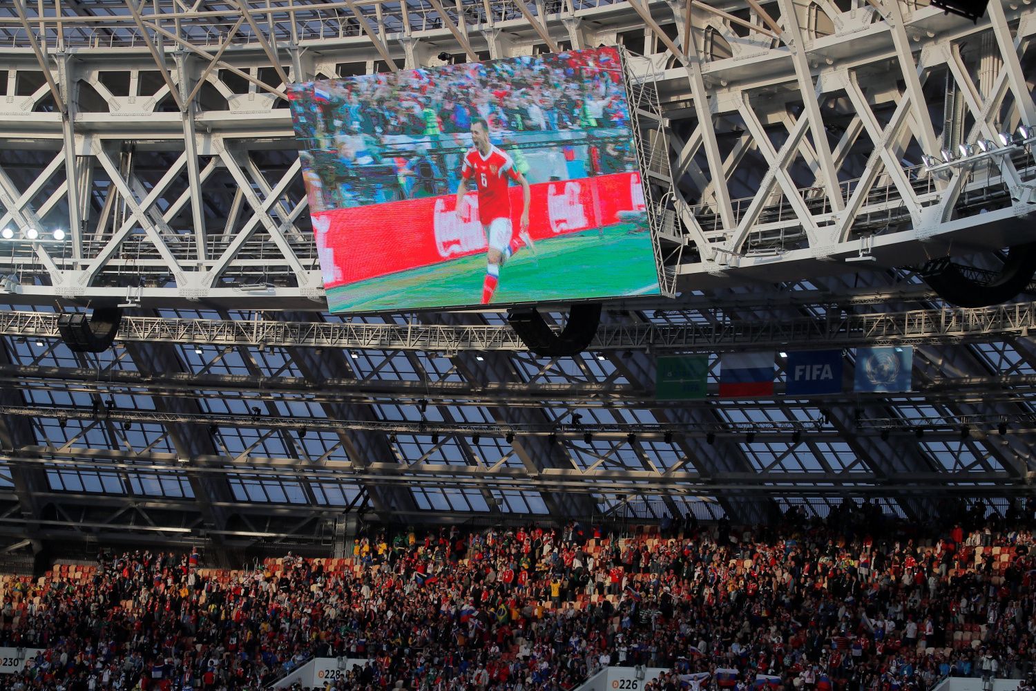 Denis Čeryšev z Ruska na obrazovce stadionu v Lužnikách slaví gól v zápase se Saúdskou Arábií na MS 2018