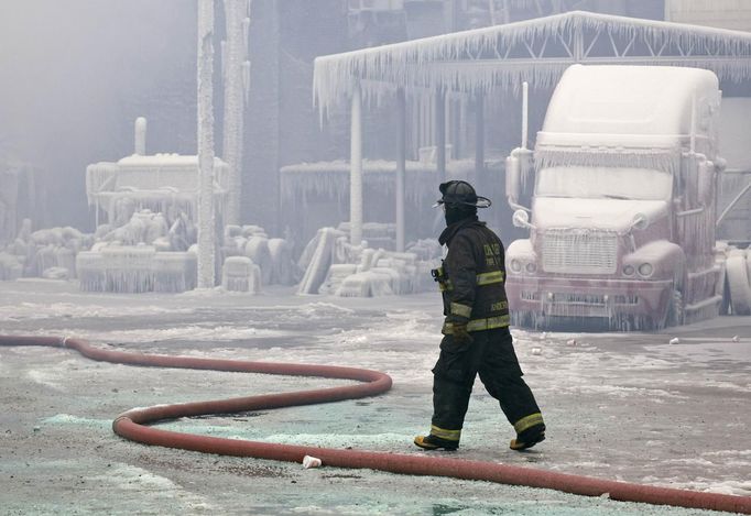 A firefighter walks past an ice covered warehouse that caught fire on Tuesday night in Chicago January 23, 2013. Fire department officials said it is the biggest fire the department has had to battle in years and one-third of all Chicago firefighters were on the scene at one point or another trying to put out the flames. An Arctic blast continues to gripped the U.S. Midwest and Northeast Wednesday, with at least three deaths linked to the frigid weather, and fierce winds made some locations feel as cold as 50 degrees below zero Fahrenheit. (minus 46 degrees Celsius) REUTERS/John Gress (UNITED STATES - Tags: DISASTER ENVIRONMENT) Published: Led. 23, 2013, 4:50 odp.