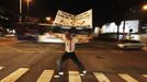 A member of the group Traffic Psychologists performs as he holds up a banner in front of traffic light in Sao Paulo July 23, 2012. Traffic Psychologists is a non-profit non-governmental organization which aims to humanize traffic and reduce the level of stress caused to drivers. Sao Paulo has more than 7 million vehicles, according to figures from the state transport authority Detran. The banner reads "A day without laughter is a day wasted". Picture taken July 23, 2012. REUTERS/Nacho Doce (BRAZIL - Tags: TRANSPORT SOCIETY) Published: Čec. 24, 2012, 6:54 dop.