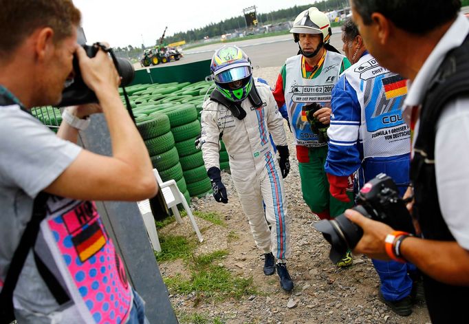 Williams Formula One driver Felipe Massa of Brazil walks off the track after crashing with his car in the first corner after the start of the German F1 Grand Prix at the