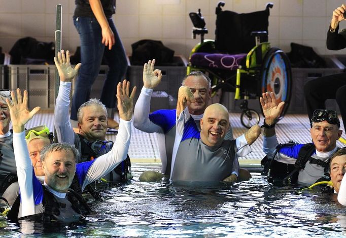 French athlete Philippe Croizon (C), whose arms and legs were amputated after an electric shock accident in March 1994, celebrates with unidentified divers in a 33 metre (36 yard) deep pool, the world's deepest pool built to train professional divers, at Nemo33 diving centre in Brussels January 10, 2013. Croizon, who swam with adapted prostheses that had flippers attached, broke a world record and became the first disabled person to dive to 33 metres, according to the organisers. REUTERS/Yves Herman (BELGIUM - Tags: SPORT DIVING SOCIETY) Published: Led. 10, 2013, 3:40 odp.