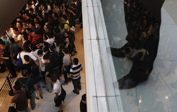 A security guard looks on as customers gather outside an Apple store before the release of iPhone 5 in Hong Kong September 21, 2012. Apple Inc's iPhone 5 hit stores around the globe on Friday, with fans snapping up the device that is expected to fuel a huge holiday quarter for the consumer giant. REUTERS/Bobby Yip (CHINA - Tags: BUSINESS SCIENCE TECHNOLOGY) Published: Zář. 21, 2012, 2:45 dop.