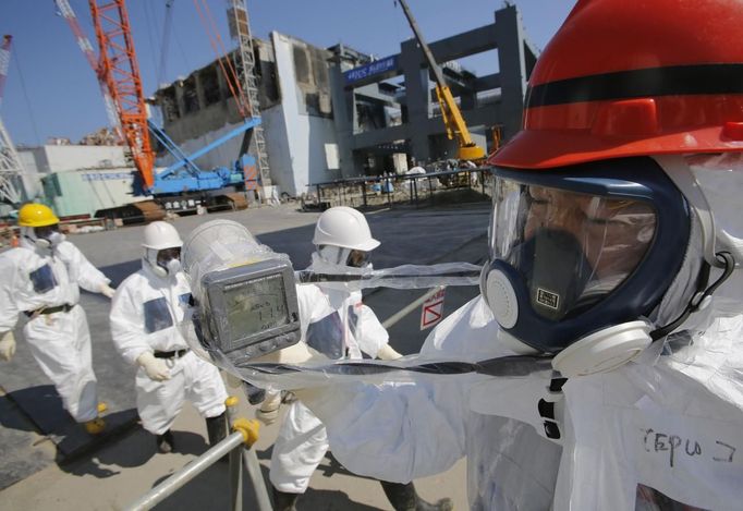 A radiation monitor indicates 114.00 microsieverts per hour near the No.4 reactor (background C) and it's foundation construction (background R) for the storage of melted fuel rods at Tokyo Electric Power Co. (TEPCO)'s tsunami-crippled Fukushima Daiichi nuclear power plant in Fukushima prefecture, March 6, 2013, ahead of the second-year of anniversary of the the March 11, 2011 tsunami and earthquake. Members of the media were allowed into the plant on Wednesday ahead of the second-year anniversary of the tsunami and earthquake, which triggered the world's worst nuclear crisis since Chernobyl. REUTERS/Issei Kato (JAPAN - Tags: DISASTER ANNIVERSARY ENERGY) Published: Bře. 6, 2013, 9:41 dop.