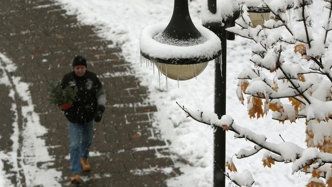 A man passes a snow covered tree and an icicled street lamp in Germering, near Munich October 28, 2012. REUTERS/Michaela Rehle (GERMANY - Tags: ENVIRONMENT SOCIETY) Published: Říj. 28, 2012, 9:33 dop.