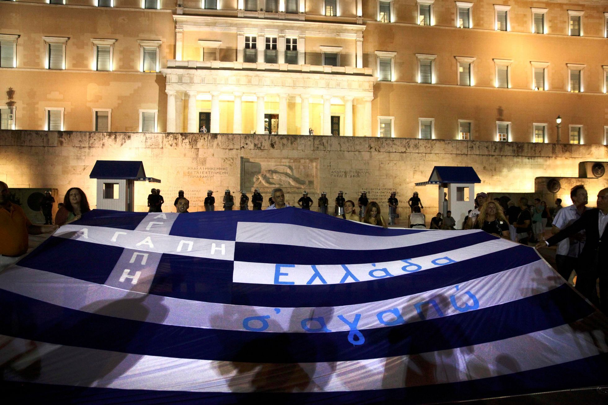 Demonstranti nesou řeckou vlajku