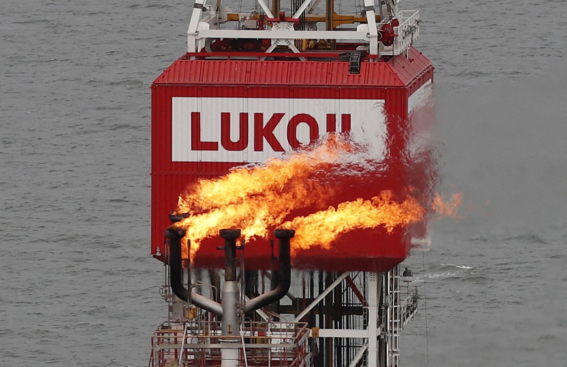 FILE PHOTO: A gas torch is seen next to the Lukoil company sign at the Filanovskogo oil platform in the Caspian Sea