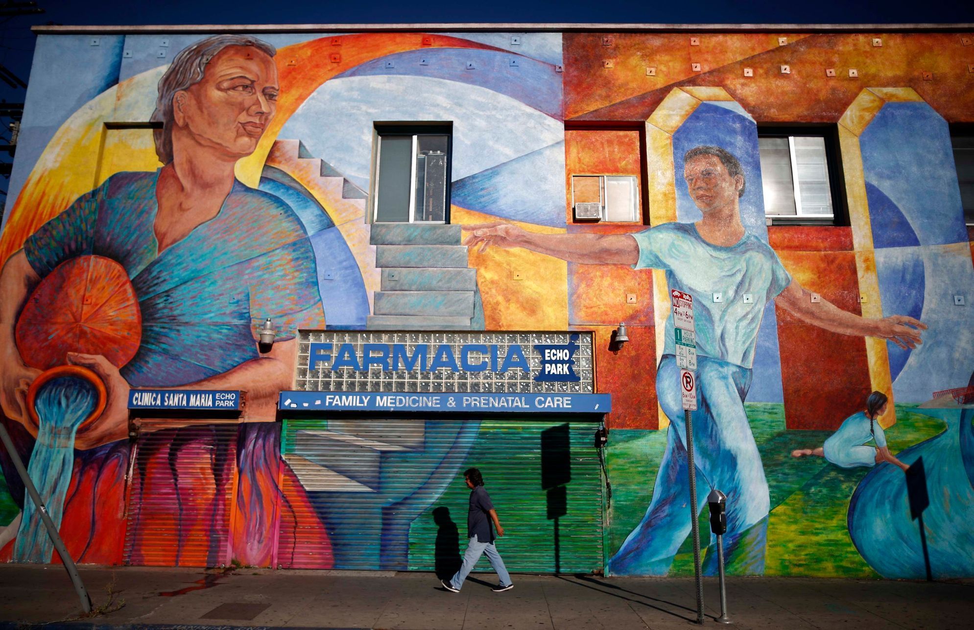 Man walks past a mural in the Echo Park area of Los Angeles, home to many Mexican and Central American migrants, in California