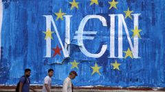 Řecko Men walk by fresh anti-EU graffiti in Athens, Greece