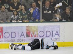 Český útočník San Jose Milan Michálek leží v bolestech na ledě poté, co ho při ostré srážce zranil kapitán Dallasu Brenden Morrow. Dallaské publikum se dobře baví (zřejmě sledováním kostky nad ledem).