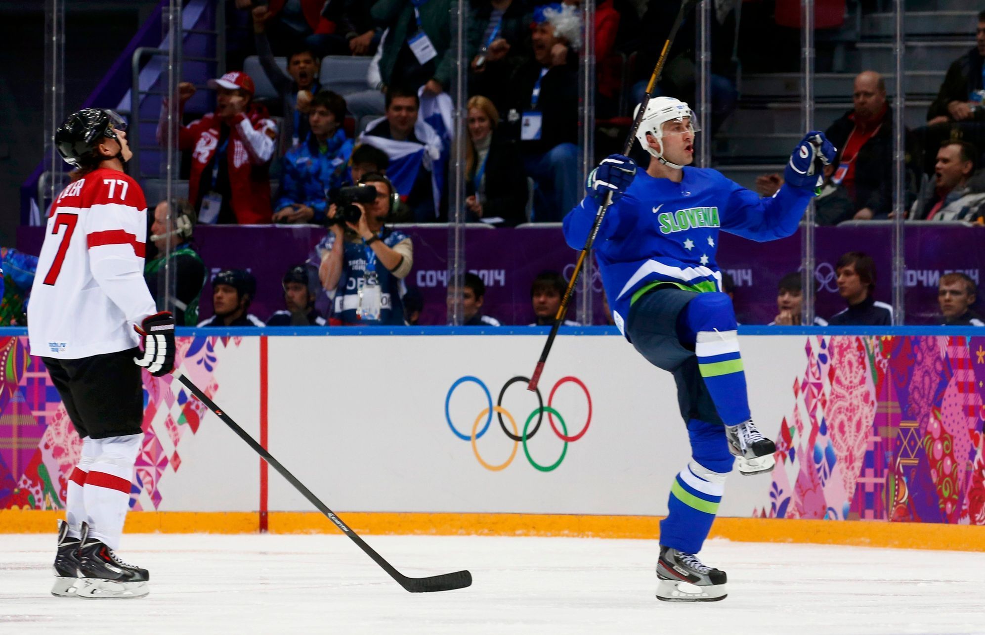 Slovenia's Kovacevic celebrates his goal as Austria's Lebler reacts during second period of their men's ice hockey playoffs qualification game at 2014 Sochi Winter Olympics