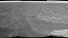 Autonomous Hazard Checks Leave Patterned Rover Tracks on Mars A dance-step pattern is visible in the wheel tracks near the left edge of this scene recorded by the navigation camera on NASA's Mars Exploration Rover Opportunity during the 2,554th Martian day, or sol, of the rover's work on Mars (April 1, 2011). The pattern comes from use of a new technique for Opportunity to autonomously check for hazards in its way while driving backwards. For scale, the distance between the parallel tracks of the left and right wheels is about 1 meter (about 40 inches). The rover team routinely tells Opportunity to drive backwards because experience has shown this is less likely to increase the amount current drawn by the drive motor in the right-front wheel. More than two years ago, the right-front wheel on Opportunity began showing signs of drawing more current than other wheels. Opportunity's twin, Spirit, had shown similar elevated current in the right-front wheel for more than a year before that wheel on Spirit stopped working in 2006. The view looks back after Sol 2554's drive at the tracks imprinted by the drive. The drive covered at total of 118.6 meters (389 feet). Rover drivers had planned the drive based on images taken from the rover's Sol 2553 location. The first portion -- which imprinted the more distant, simpler, tracks -- was a backward "blind" drive. Rover drivers command blind drives -- either forward or backward -- when they can assess the safety of the terrain well enough from the images taken at the drive's starting point that they don't need the rover to pause and look for obstacles along the route. For the Sol 2554 drive over flat ground, the drivers chose a blind drive of 100 meters (328 feet). They commanded Opportunity to begin using backward autonomous navigation after it reached the end of the blind drive on that sol. That "backward autonav" driving imprinted the nearest portion of the tracks visible here. The rover team began using the backward autonav strategy last year as a modification of forward autonav, which the team has used since the rovers' first year on Mars. In autonav mode, the rover pauses periodically during a drive, uses its stereo navigation camera to view the route in the intended drive direction, analyzes the images for potential hazards in the route, and makes a decision about what to do based on that analysis. One catch, when driving backwards, is that the navigation camera's view is partially blocked over the rear of the rover by the low-gain antenna. So, lest a hazard be hidden behind that antenna, the backward autonav technique includes turning the rover 17.5 degrees away from the drive direction just before taking the navigation camera images. This gives the camera an unobstructed view in the drive direction. This little maneuver -- repeated every 1.2 meters -- is what created the dance-step pattern in the foreground portion of the rover tracks in this image. In forward autonav, Opportunity can plot its own way around an obstacle and continue driving. In backward autonav, Opportunity just ends the drive for the day if the onboard analysis of images detects a hazard in the route. On the level terrain Opportunity has been crossing this spring on the trek from Santa Maria crater toward Endeavour crater, obstacles are few, so backward autonav has significantly extended the distance the rover can cover in one sol's driving. This mosaic combining several pointings of the navigation camera is presented in a cylindrical projection. The center of the image is toward the northeast, and the full view covers a sweep of 252 degrees, from westward on the left to southeastward on the right. Opportunity has been exploring the Meridiani Planum region of Mars since early 2004 in a mission originally planned to last for three months. Both Opportunity and Spirit have made important discoveries about wet environments on ancient Mars that may have been favorable for supporting microbial life. NASA's Jet Propulsion Laboratory, a division of the California Institute of Technology in Pasadena, manages the Mars Exploration Rover Project for NASA's Science Mission Directorate, Washington. Image Credit: NASA/JPL-Caltech