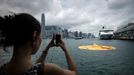 A woman takes a picture of the 16.5-metre-tall inflatable Rubber Duck art installation as it lies deflated in Hong Kong's Victoria Harbour on May 15, 2013. Organisers said the inflatable Rubber Duck created by Dutch artist Florentijn Hofman had been deflated for scheduled maintenance, but visitors who had made the trip to see it were left disappointed.